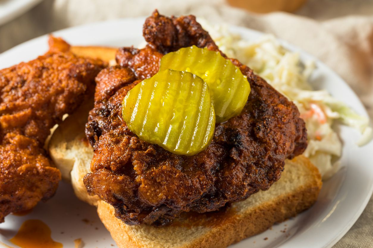 Nashville hot chicken served with pickles and bread at a budget-friendly restaurant near Baymont Nashville Airport