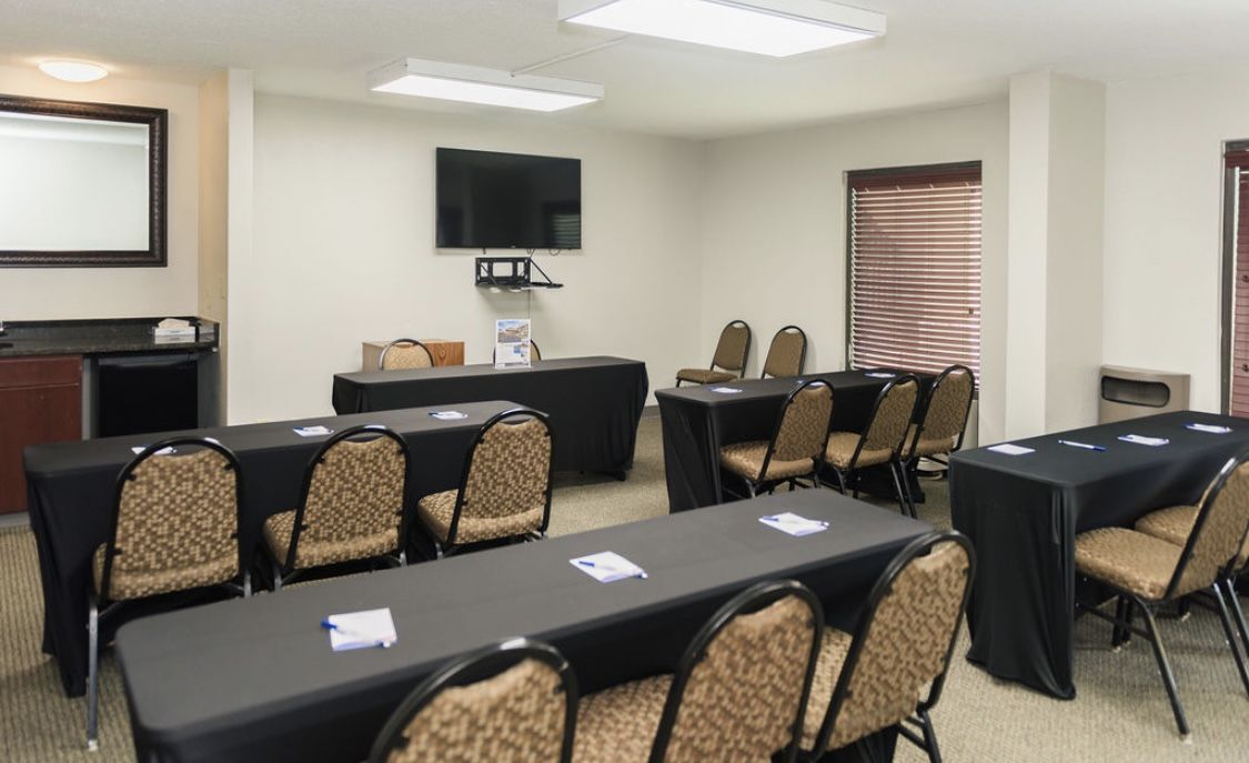 Budget-friendly meeting room near Nashville Airport with tables, chairs, TV, and whiteboard at Baymont by Wyndham